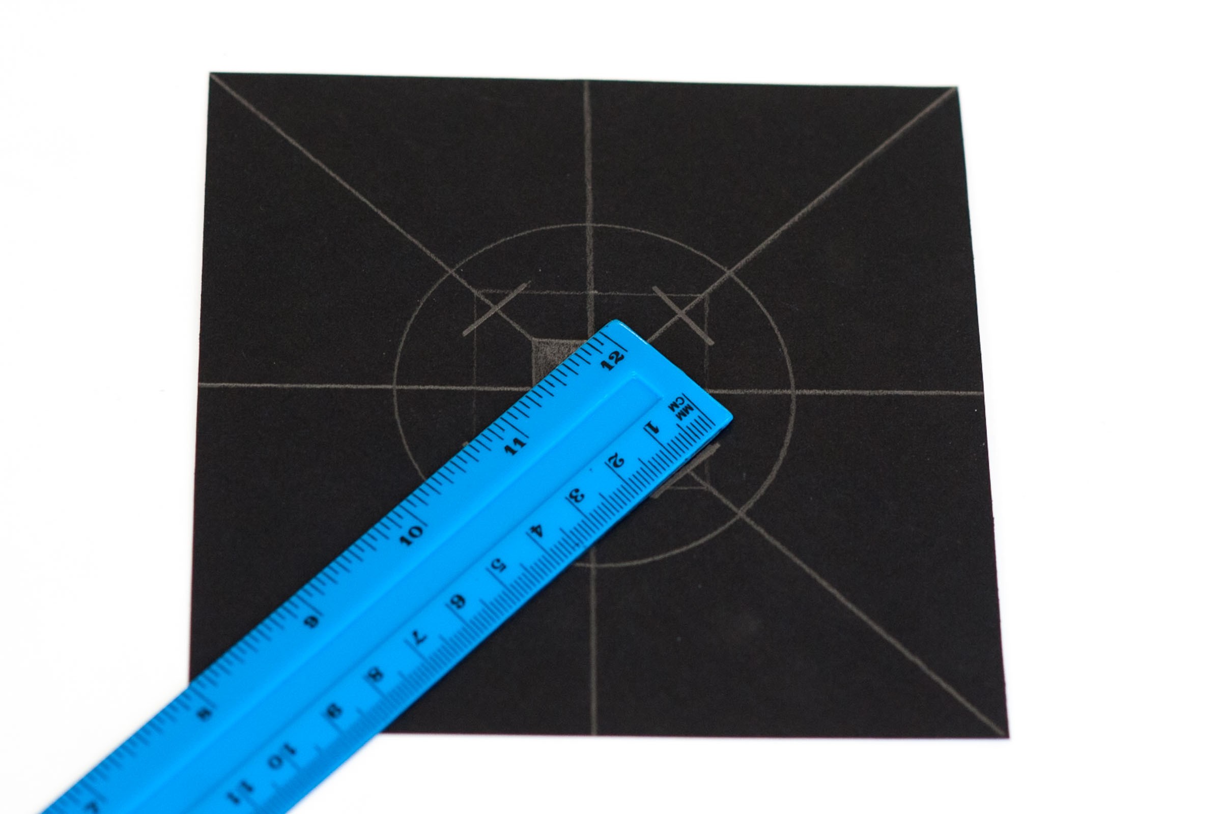 Teken om het middelste vierkantje een groter vierkantje van 4x4cm. Op de hoeken teken je schuine snijlijnen.