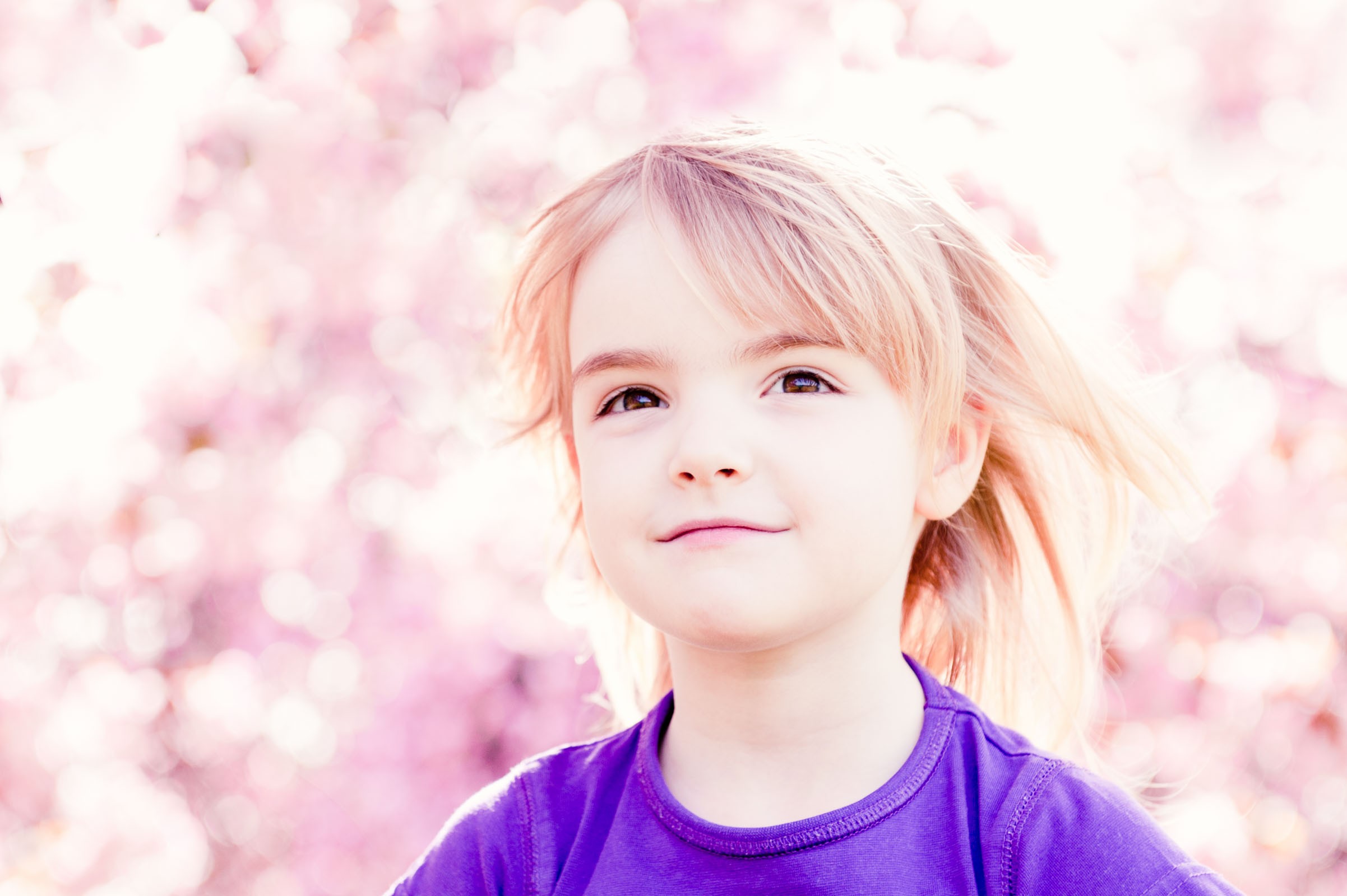 Het meisje zat op de schouders van haar vader. De bloesem vormde een mooie roze achtergrond.