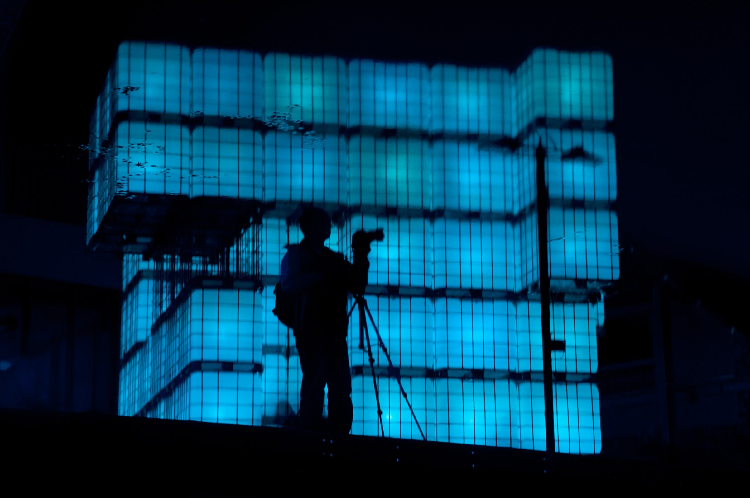 De reflectie in het water van een fotograaf met statief.