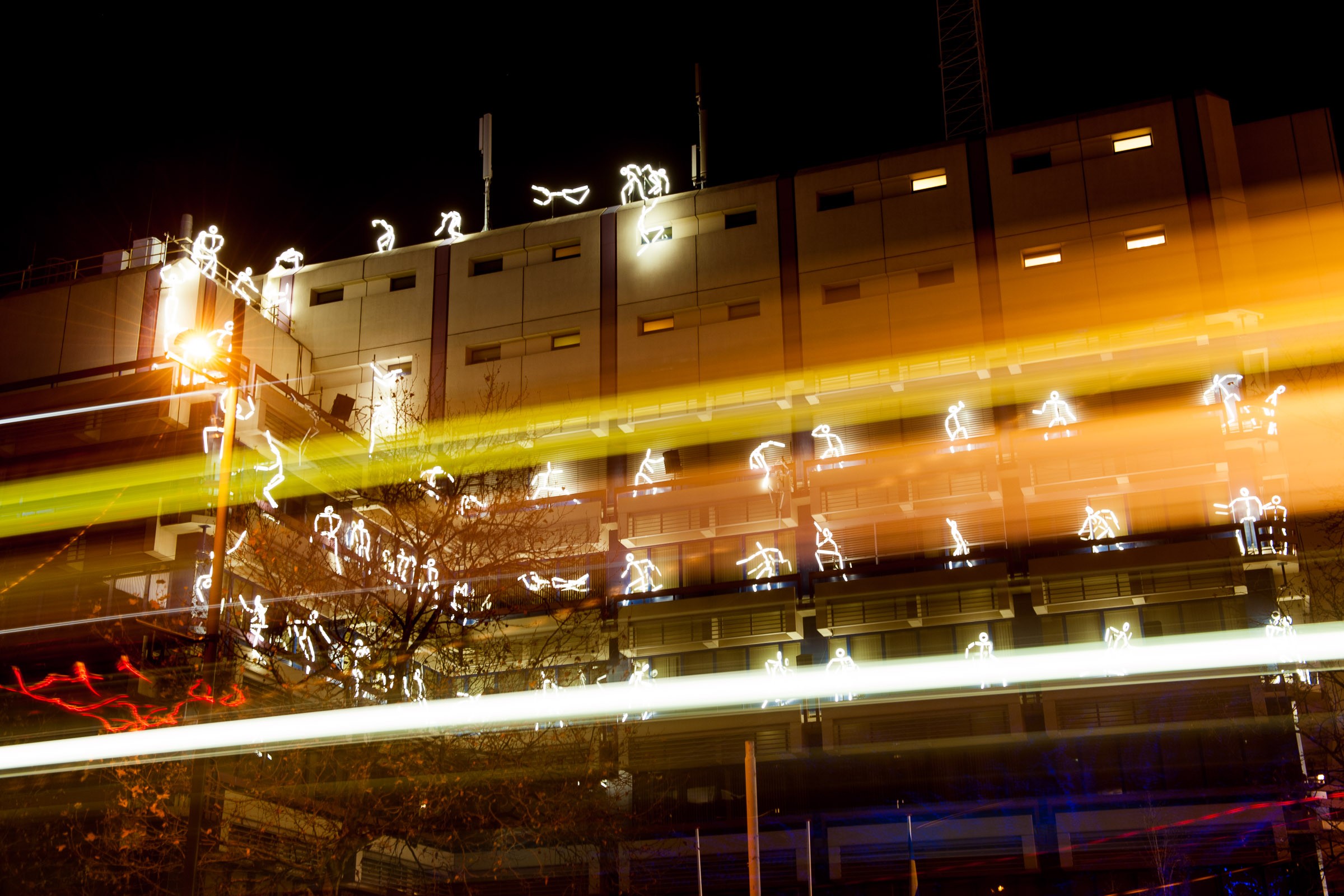Door te fotograferen met een lange sluitertijd zijn meerdere poppetjes in beeld zichtbaar. De lichtstrepen van een voorbijrijdende bus maken de foto ook kleurrijker en dynamischer.