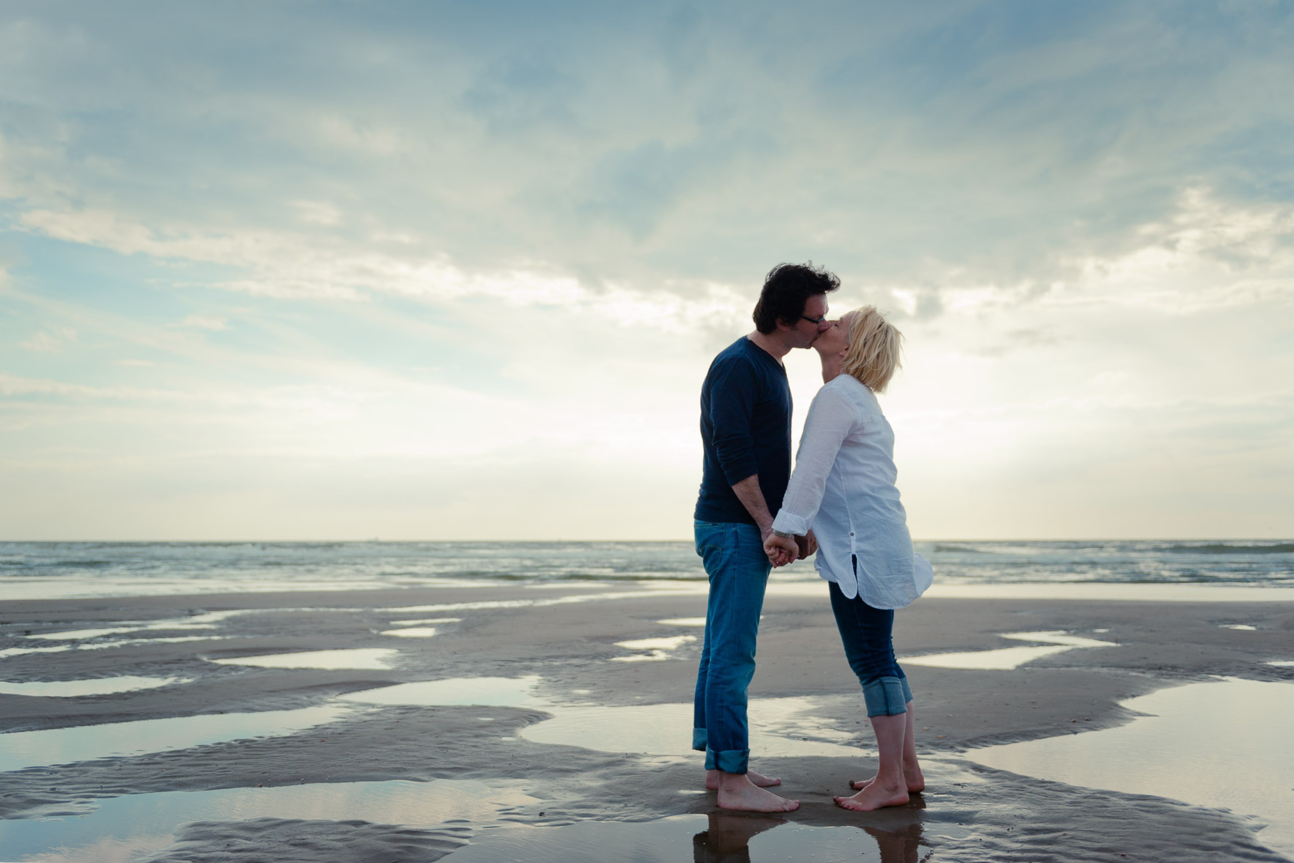 Stelletje op het strand dat elkaar een kus geeft