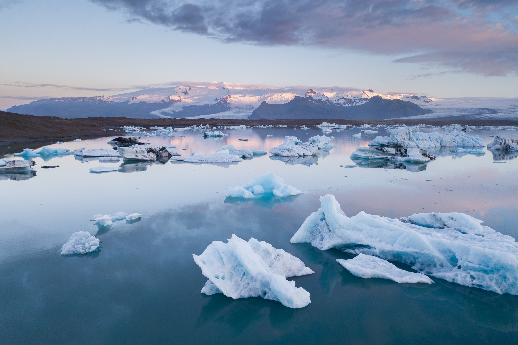 Meer met ijsschoten en op de achtergrond bergen.