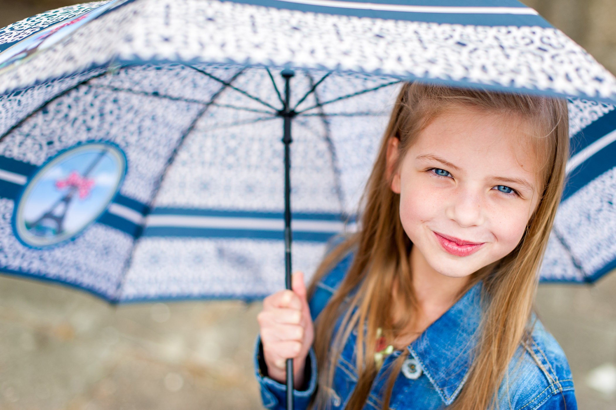 Door het grote diafragma is de voorkant van de paraplu en de achterkant alweer onscherp. De aandacht gaat daarom naar het gezicht van het meisje.