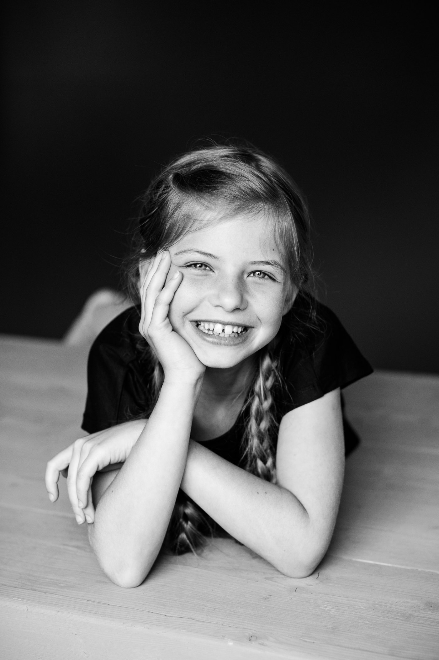 Het meisje lacht rechtstreeks naar de camera. Door de afstand zie je ook haar armen.