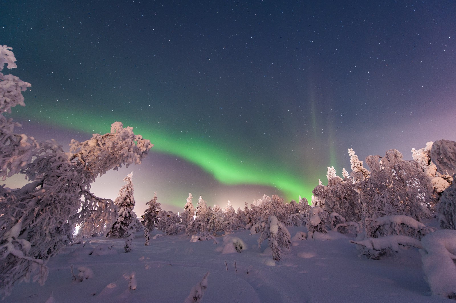 Noorderlicht fotograferen in een besneeuwd landschap met erboven een sterrenhemel.