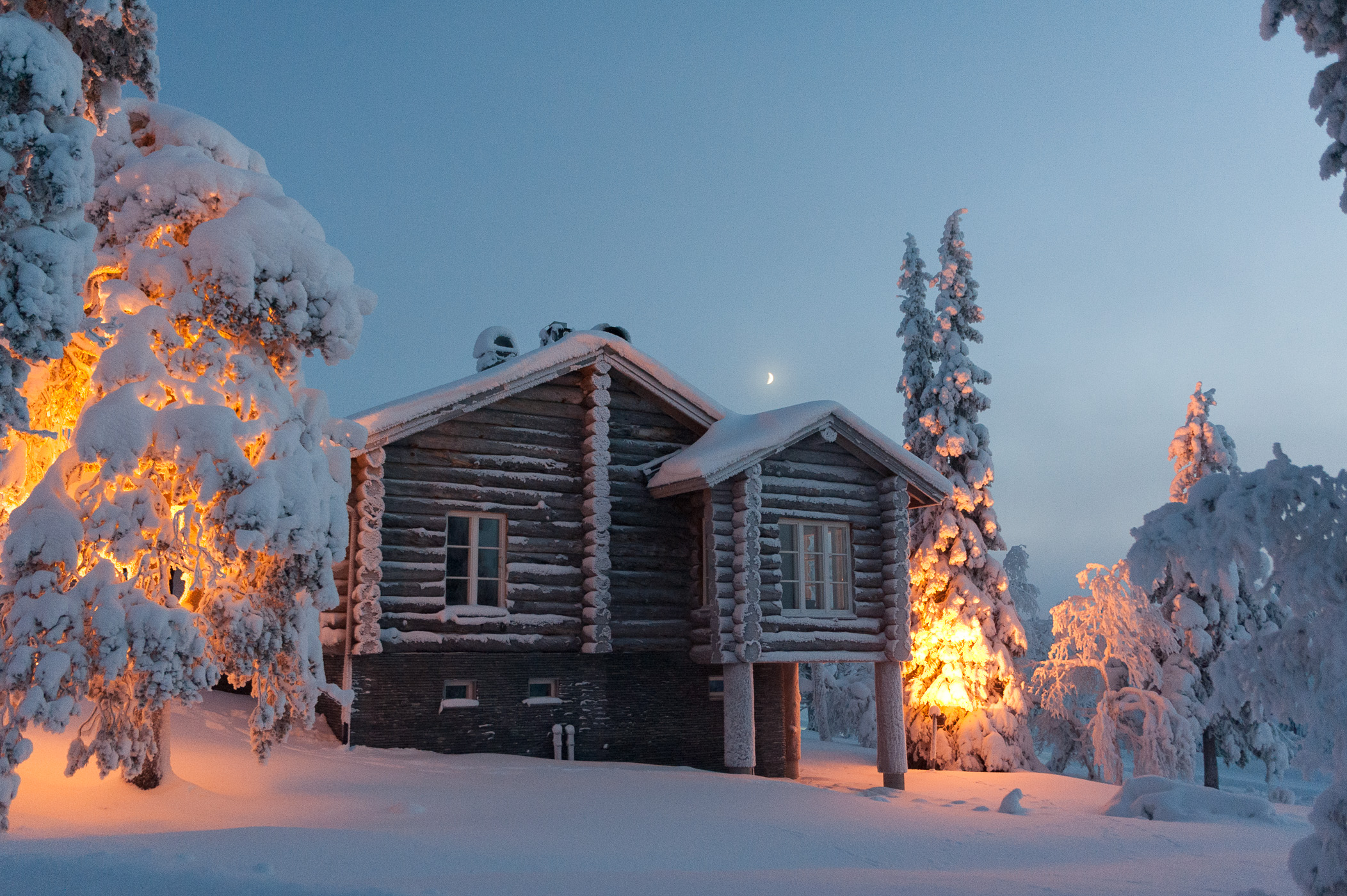 Kleine maan boven huisje in de sneeuw
