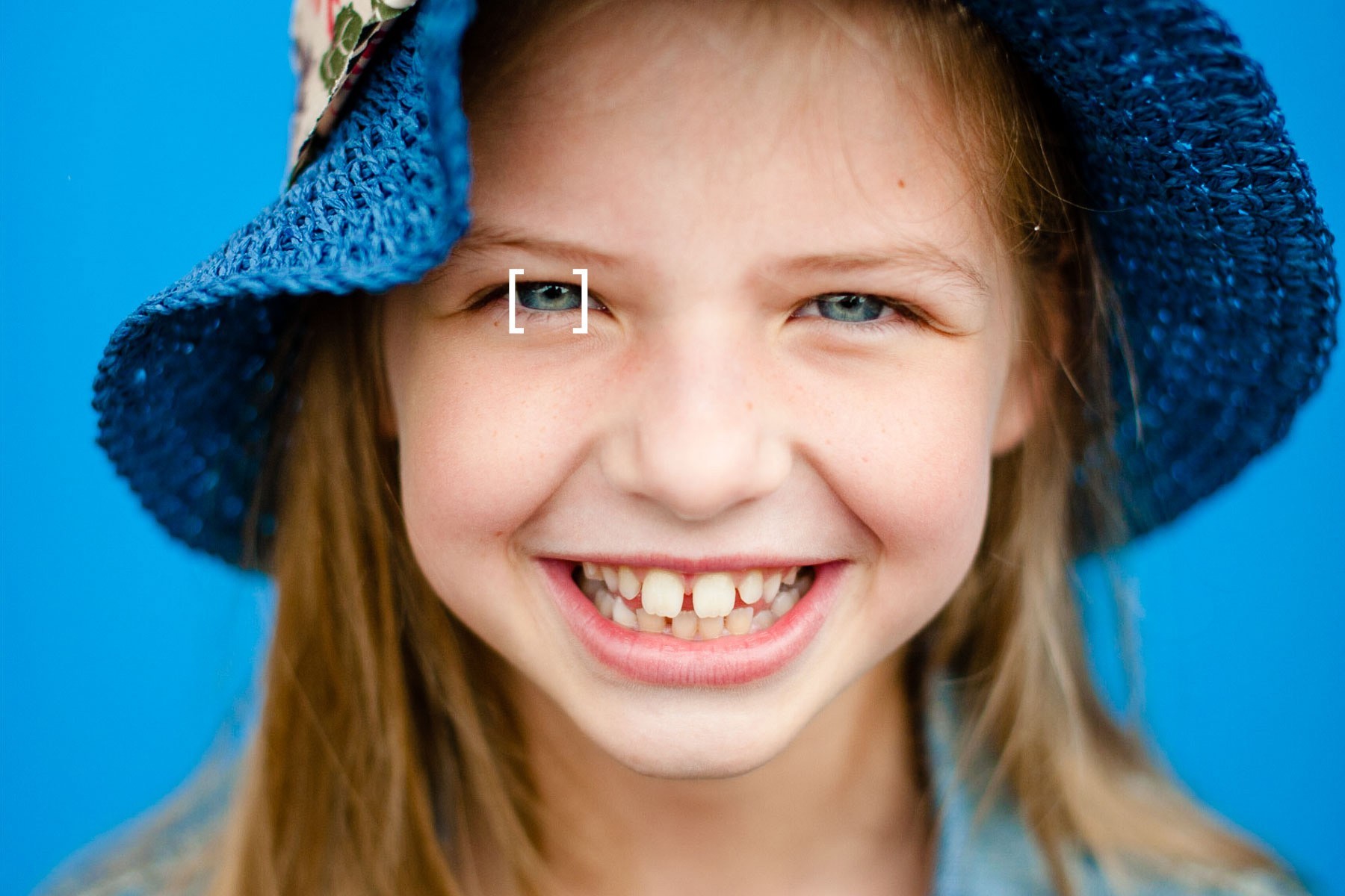 Deze portretfoto heeft weinig scherptediepte. Haar ogen zijn scherp, maar haren oren en het randje van de hoed zijn wazig. 