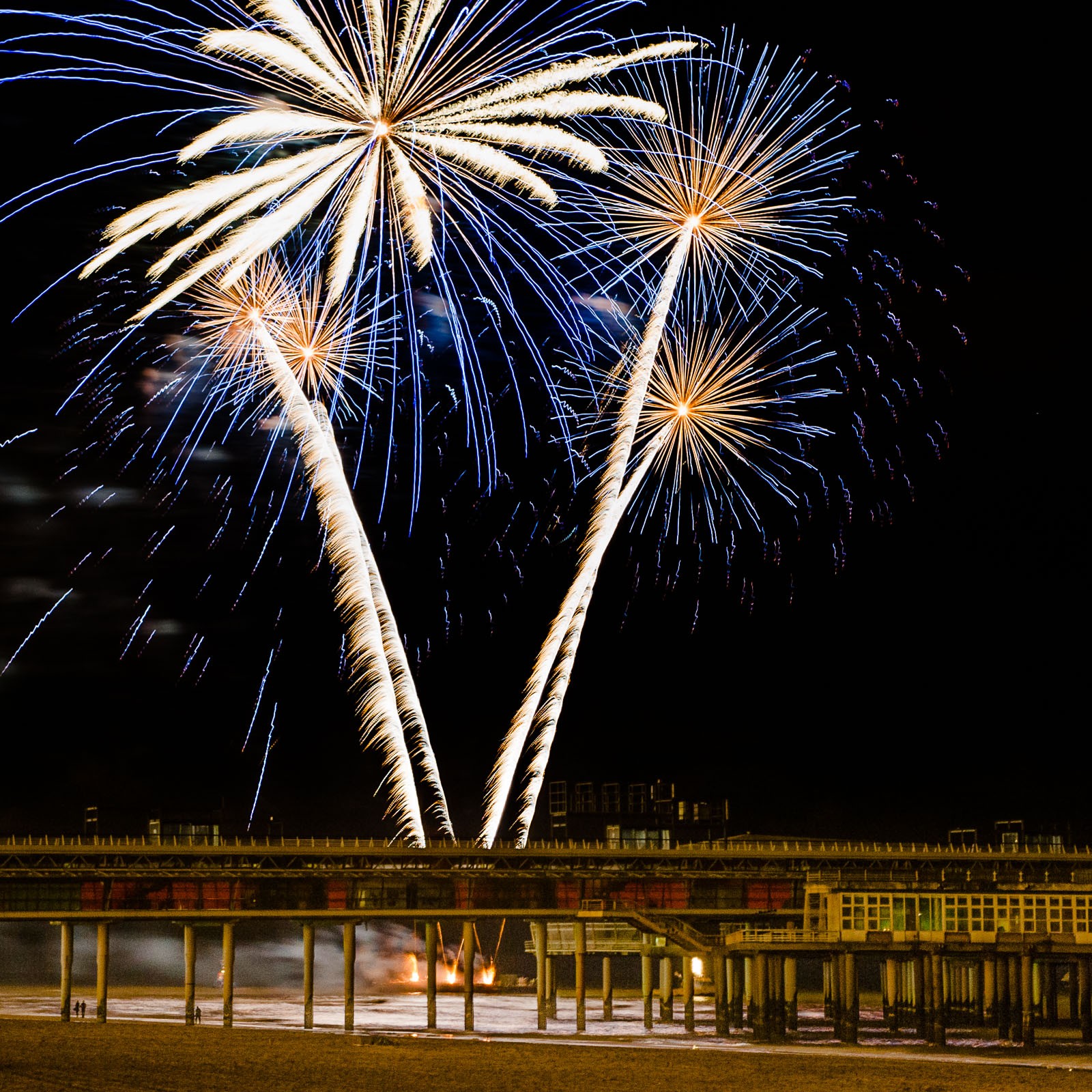 Bij de vuurwerkshow in Scheveningen besloot ik dat ik de laatste show wilde fotograferen vanaf een ander standpunt. Om de pier van Scheveningen in beeld te krijgen fotografeerde ik op een flinke afstand. De kleine mensen onder de pier gever de hoogte van het vuurwerkwerk goed weer.