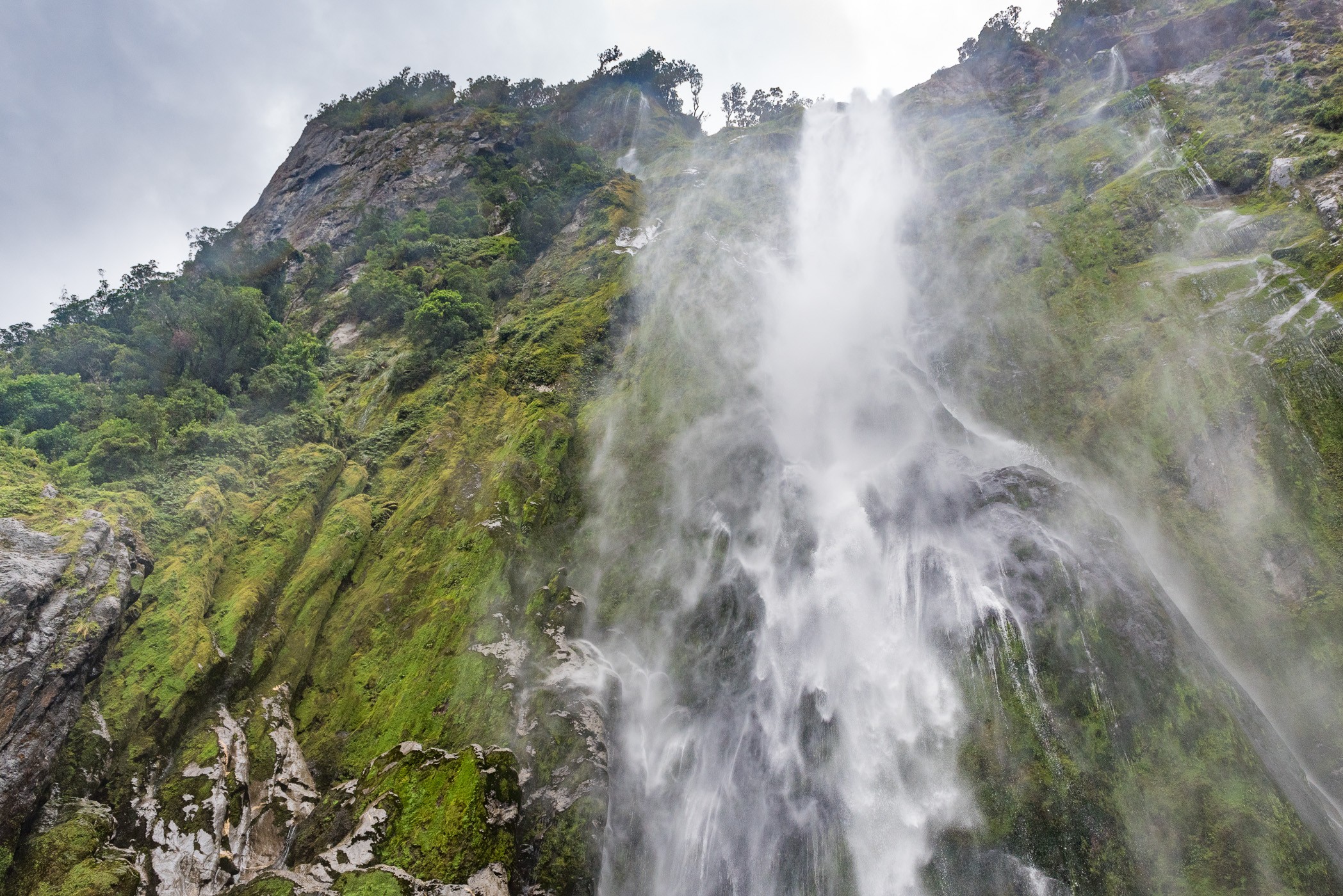 Als je recht onder een waterval staat, zie je niet goed hoe hoog is is. Zo dicht op een waterval lukt je maar heel kort zonder druppels op de lens. Voor deze foto haalde ik de lensdop van mijn camera en schoot direct een paar foto's. Hierna zaten er alweer teveel druppels op.